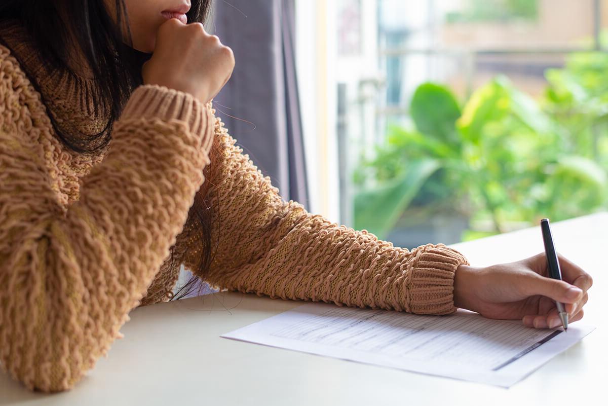 Close up of a women filling in a paper form with a pen